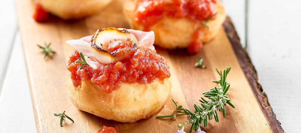Pizzette con polpa fine di pomodoro, cipolle grigliate e pancetta dolce Pizzette con polpa fine di pomodoro, cipolle grigliate e pancetta dolce
