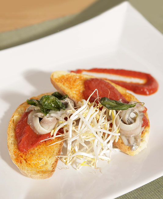 Bruschetta-leivät marinoiduilla sardelleilla ja tulisella tomaattikastikkeella Bruschetta-leivät marinoiduilla sardelleilla ja tulisella tomaattikastikkeella